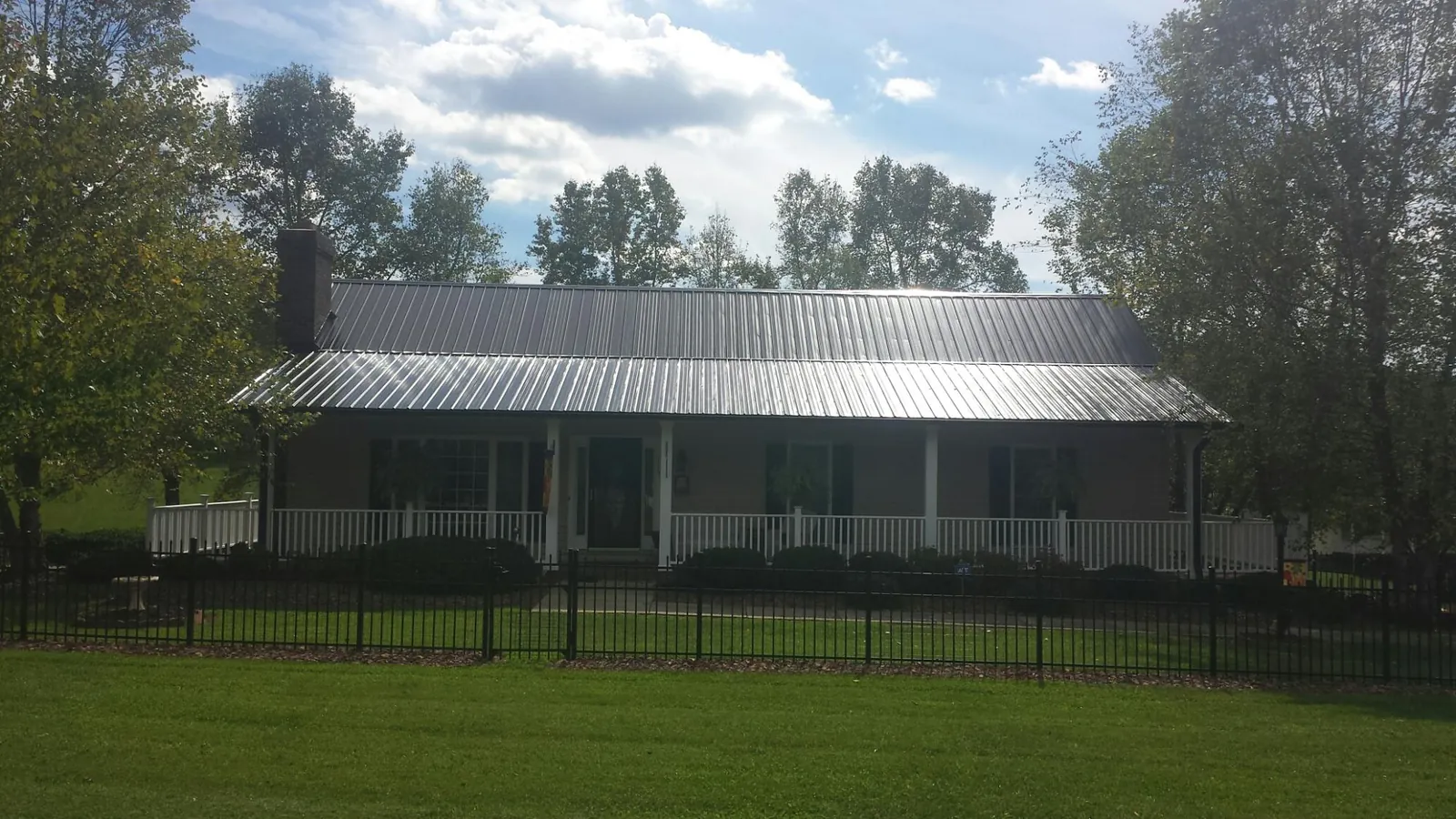 Gray metal roof on a brick ranch with a full width front porch — Gutter Guard Installation work by our crew in Hebron